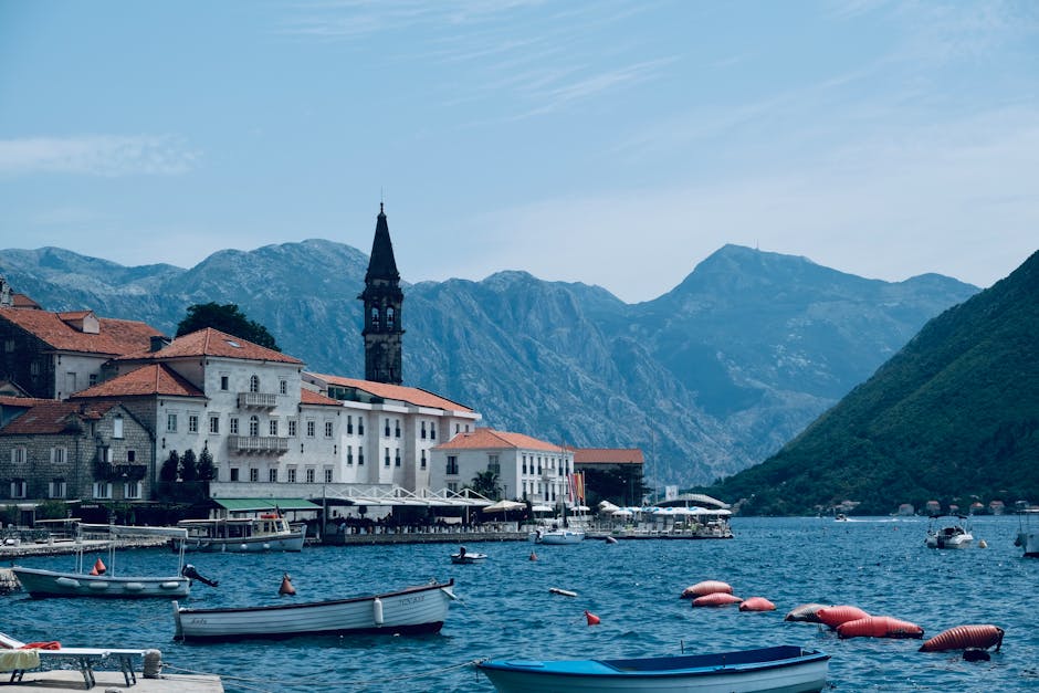 Boats moored in Bay of Kotor with bell tower and mountains, Montenegro