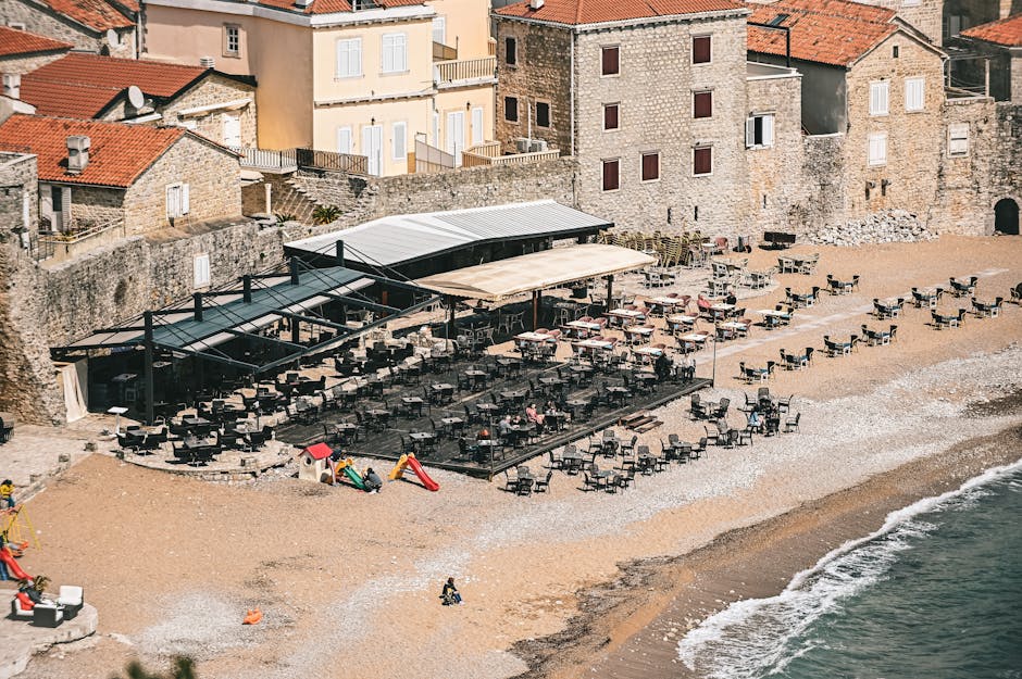 Spiaggia rocciosa con bar, sedie e mura antiche del Montenegro