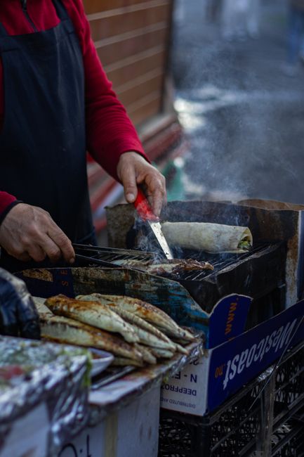 Venditore cuoce pesce alla griglia in bancarella di strada del Montenegro