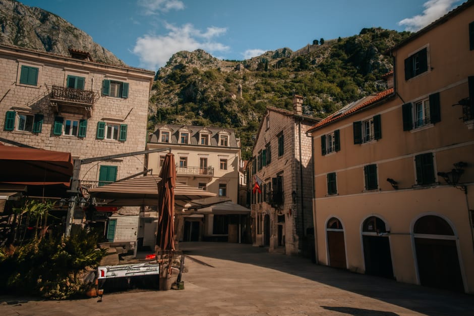 Piazza tranquilla con edifici in pietra e montagne a Kotor, Montenegro