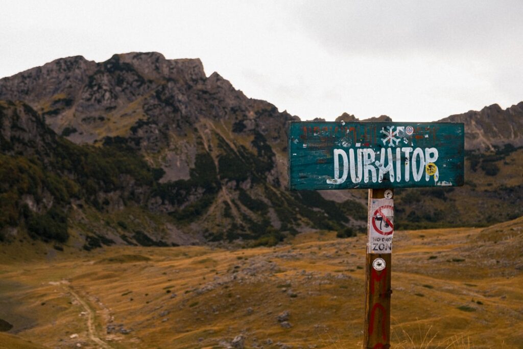 Weathered Durmitor sign on post with Montenegro mountains and plateau