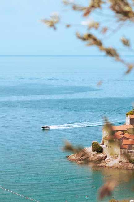 Łódka przecina turkusowe wody przy wysepce Sveti Stefan, Czarnogóra.