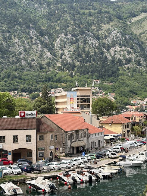 Porticciolo con barche ormeggiate e tetti rossi sotto le montagne del Montenegro