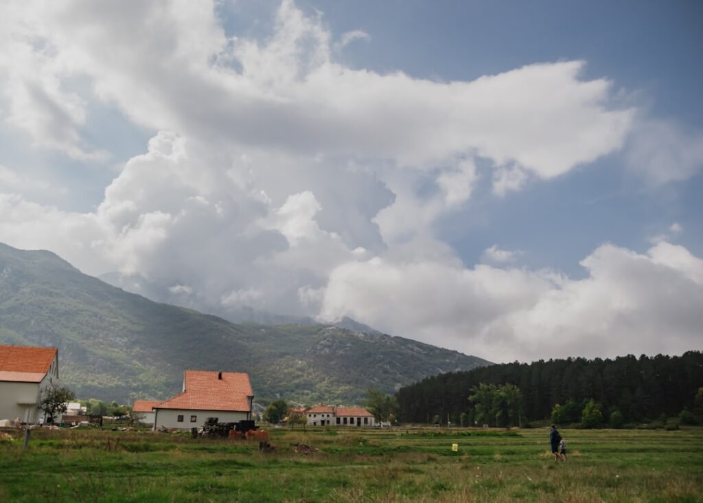 Rural houses and dramatic clouds over Montenegrin mountain fields