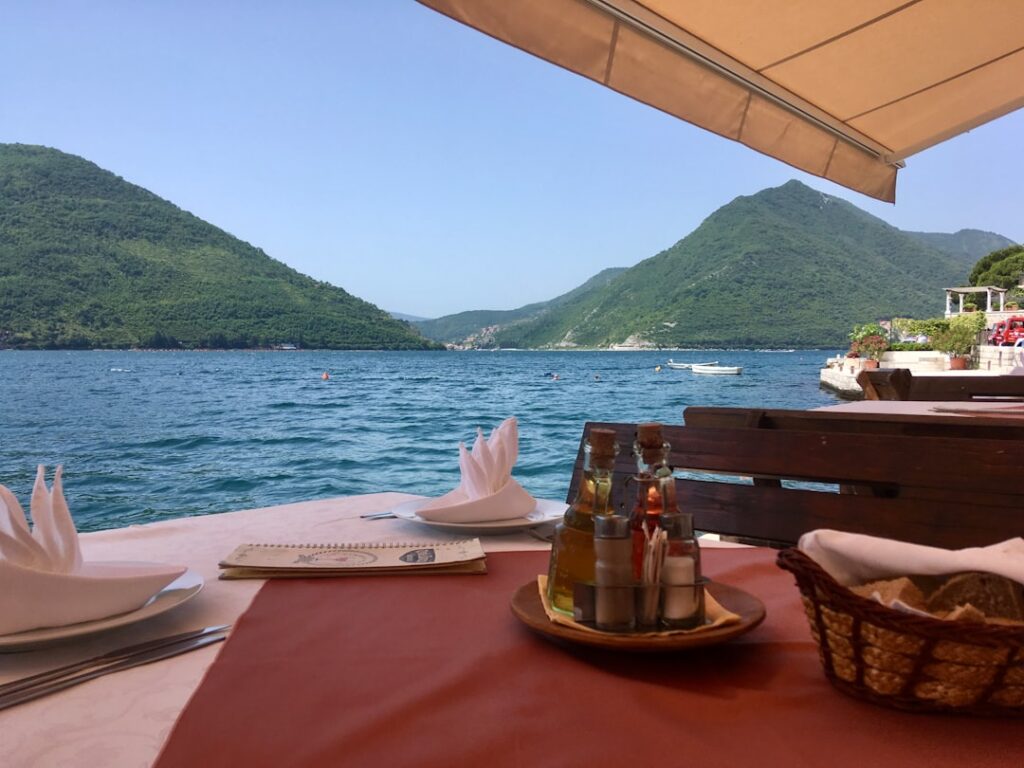 Waterfront restaurant table facing Adriatic and green mountains in Montenegro