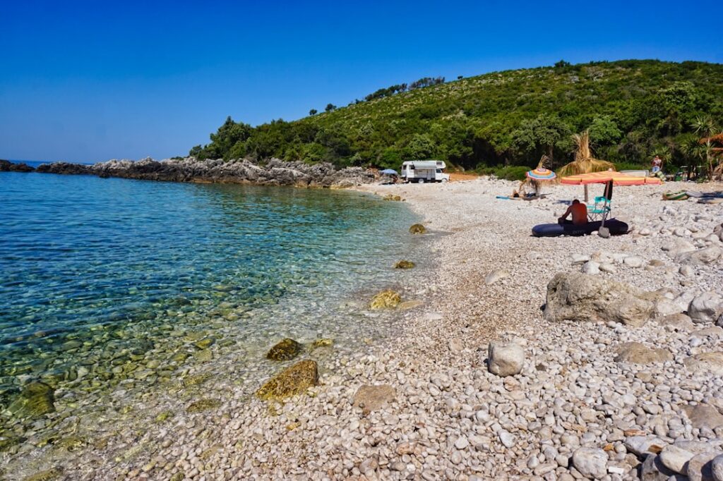 Spiaggia di sassi nascosta sotto villaggio terrazzato, Albania