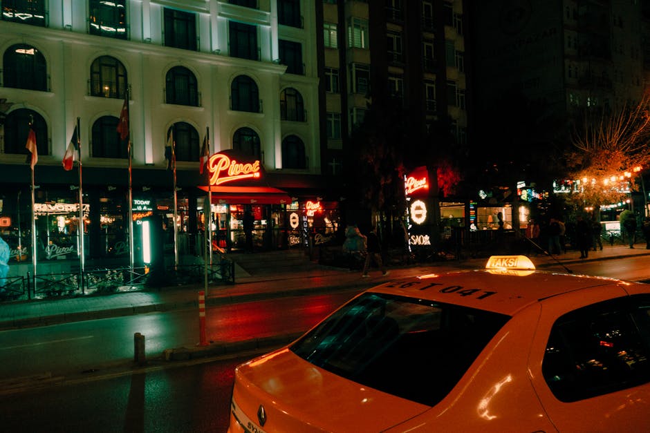 Taxi jaune arrêté devant restaurants et néons nocturnes dans la ville
