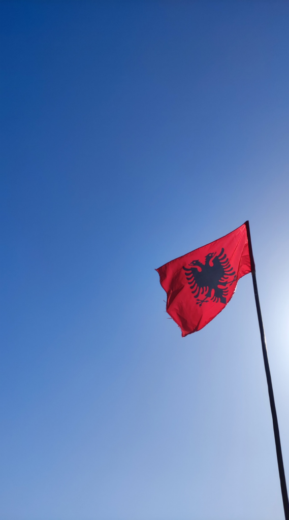 Drapeau rouge albanais à l'aigle noir flottant sous un ciel bleu