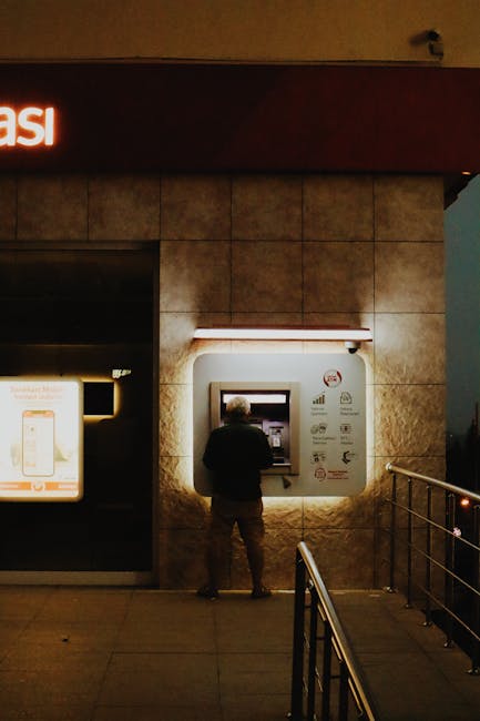 traveler withdrawing money at ATM inside bank at night