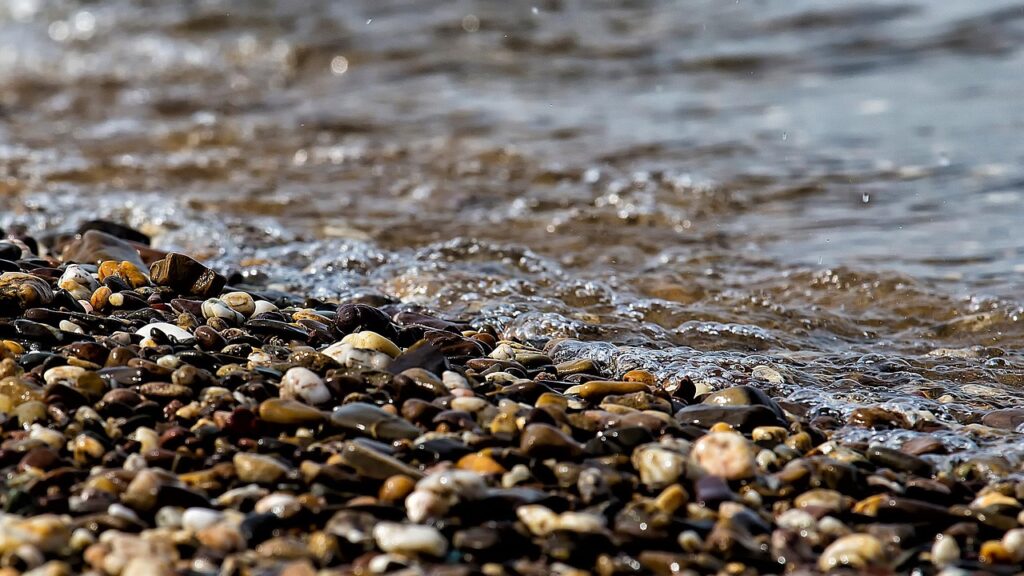 Gros plan sur galets humides bordés par de petites vagues