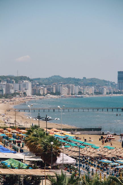 Plage bondée d'ombrelles colorées et littoral urbain en Albanie