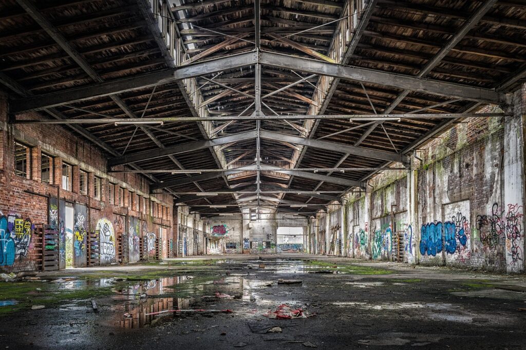 Hangar abandonné couvert de graffitis, flaques et débris au sol, Albanie