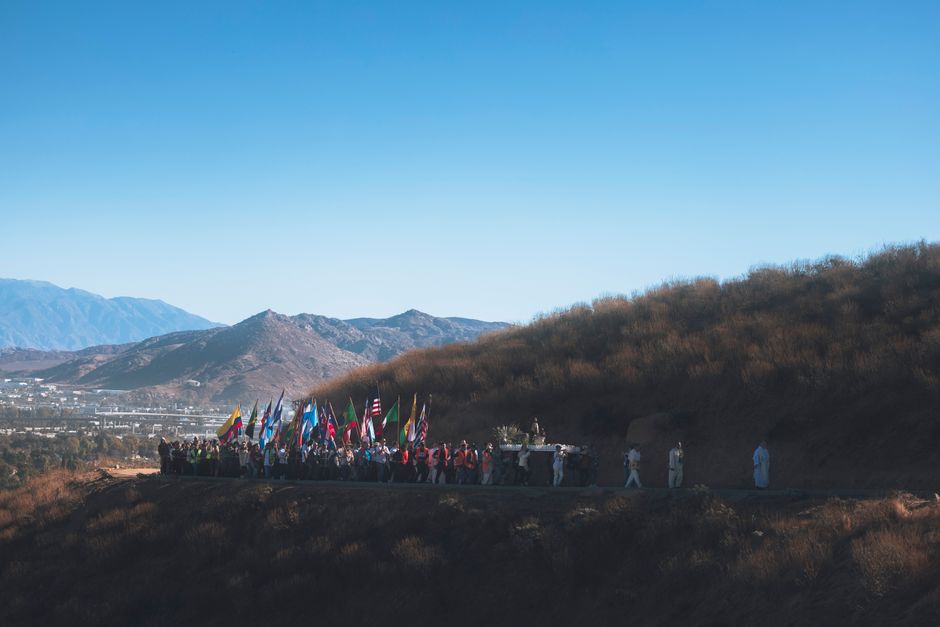 Procession avec drapeaux sur une crête, paysage rural d'Albanie