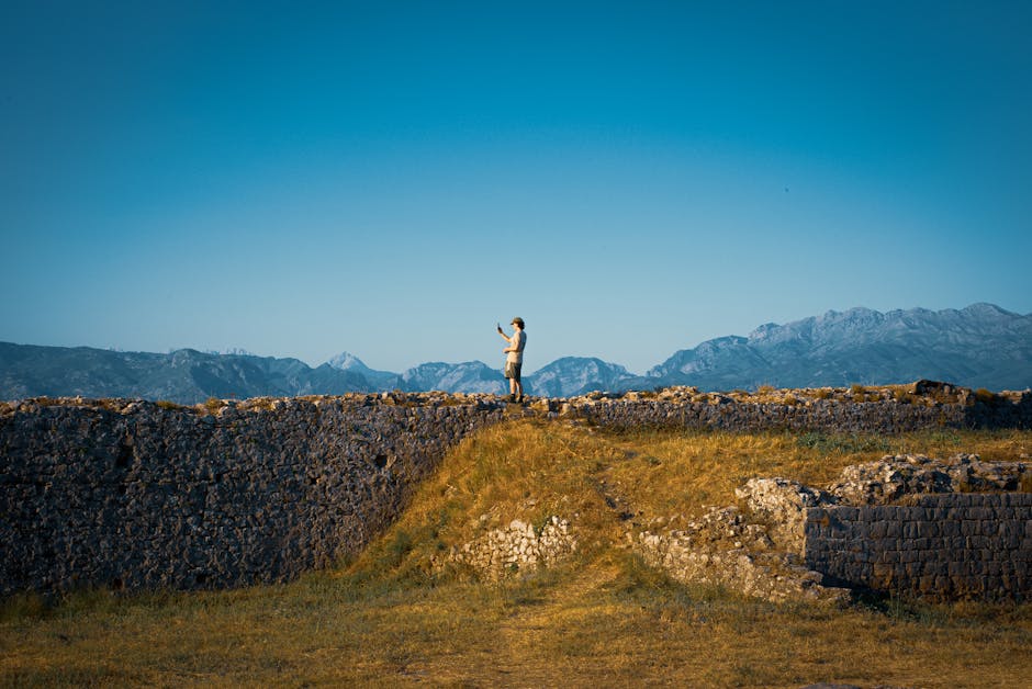 Camminatore solitario su mura antiche con montagne sullo sfondo in Albania
