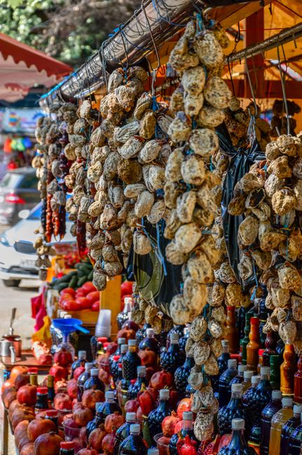 Étals de marché albanais avec guirlandes de fruits secs et bouteilles