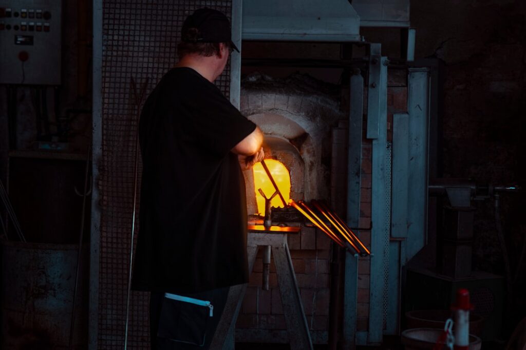 Glassblower finishing artwork Murano furnace glow