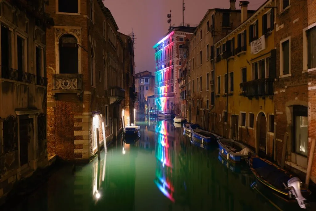 Canal nocturne à Venise avec façades éclairées aux néons colorés