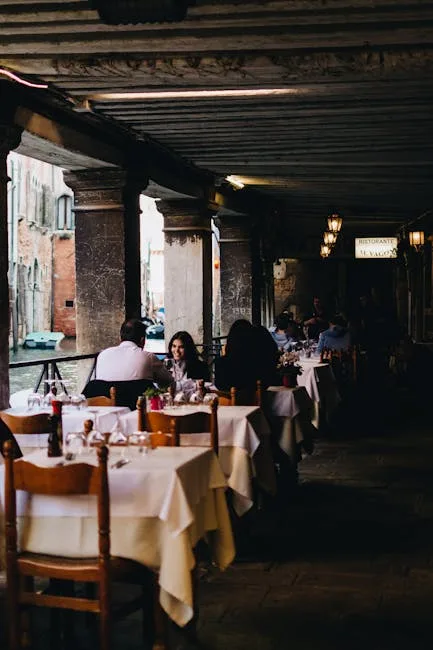 Terrasse de restaurant sous arcade le long d'un canal à Venise