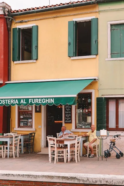 Deux hommes attablés devant une osteria colorée sur une rive à Venise