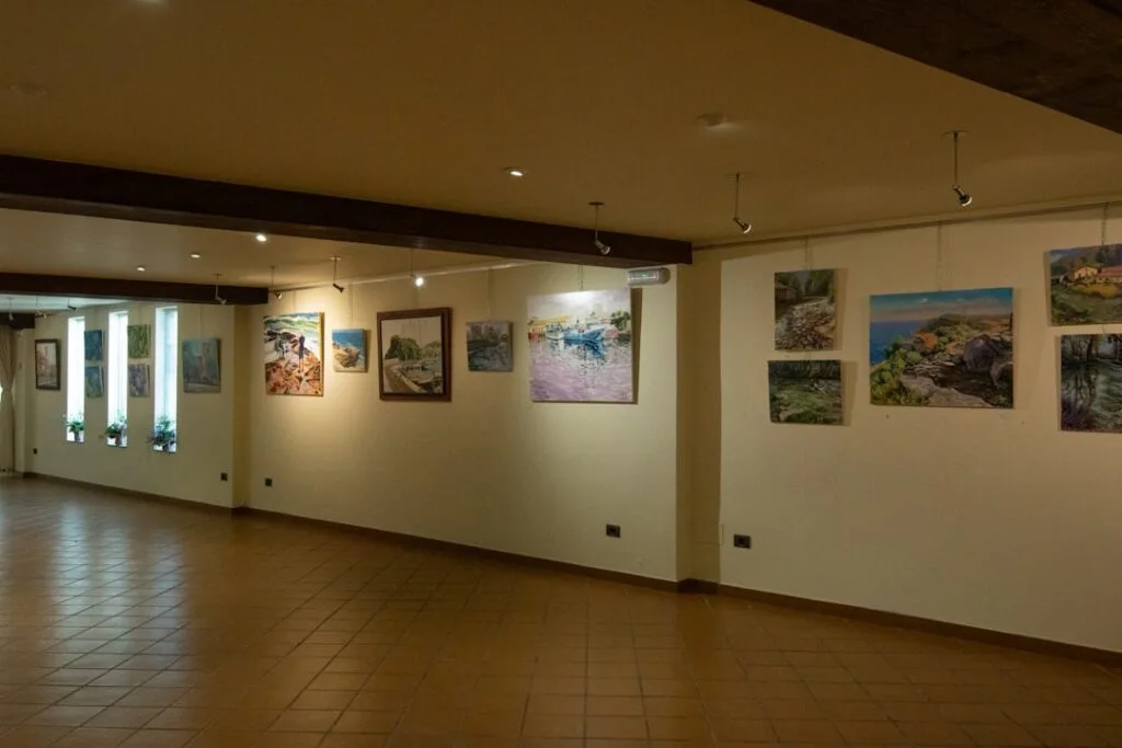 Salle d'exposition vénitienne avec peintures accrochées aux murs et sol carrelé.