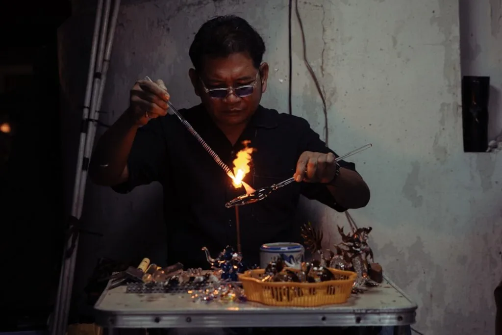 Artisan souffleur de verre travaillant au chalumeau dans un atelier vénitien