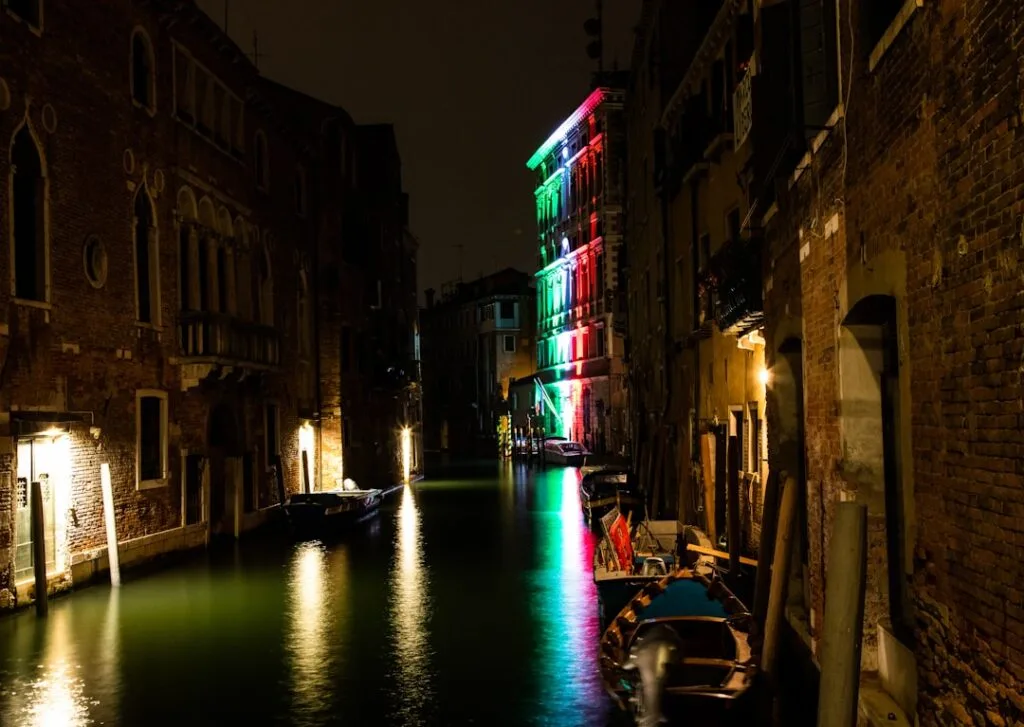 Canal nocturne à Venise, reflet coloré d'un bâtiment aux lumières