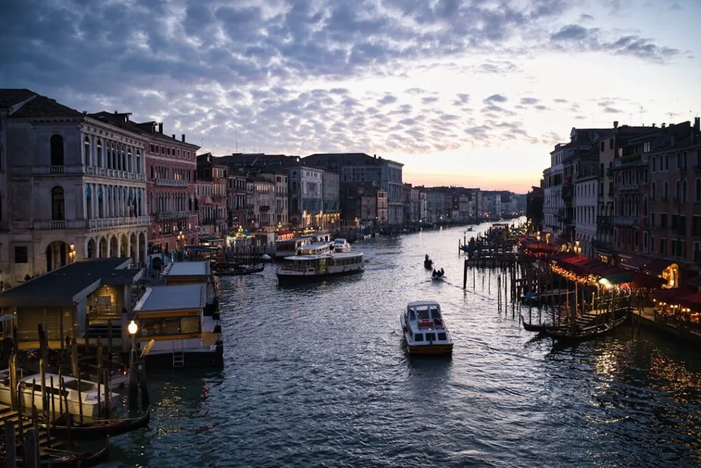 Grand Canal de Venise au crépuscule, bateaux et façades illuminées.