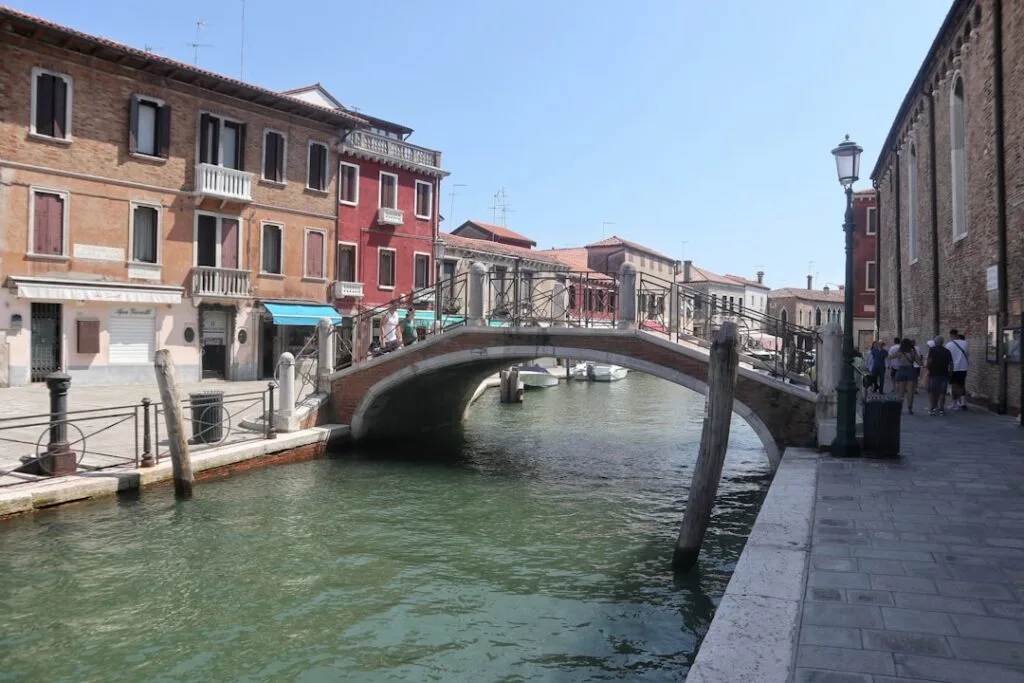 Petit pont arqué traversant un canal à Venise, façades colorées.