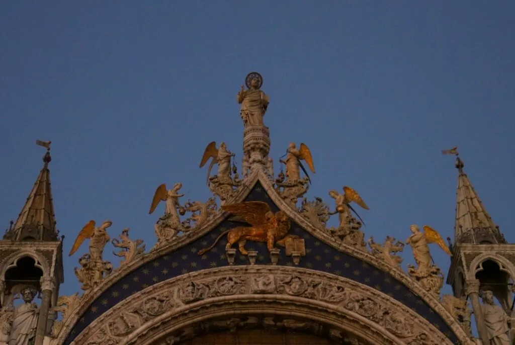 Statues et lion ailé doré sur la façade gothique à Venise