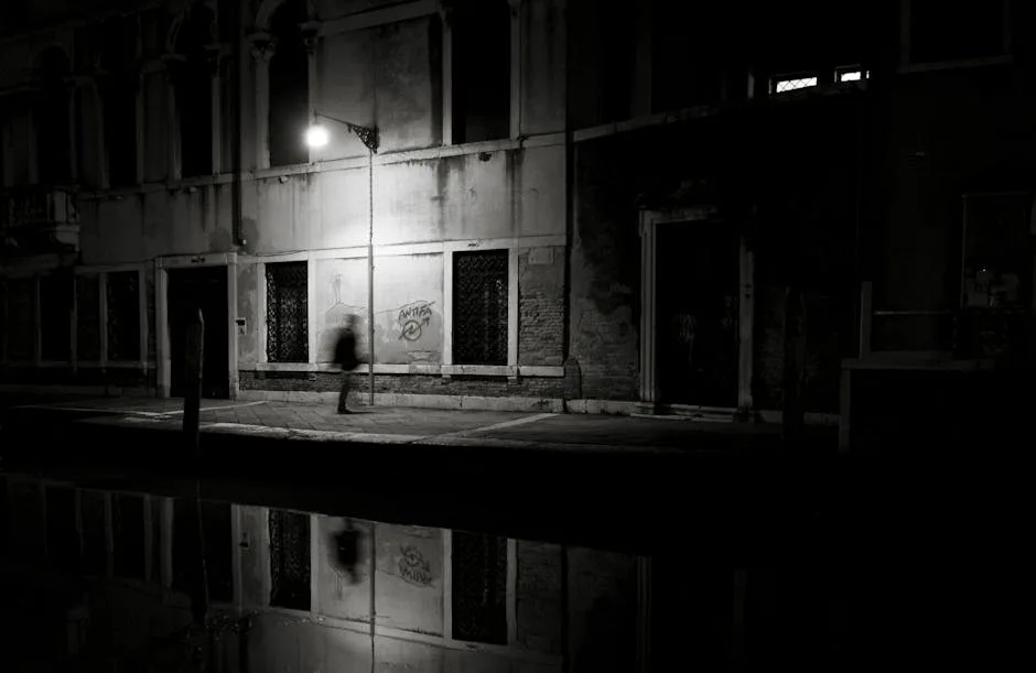 Passant flou marchant le long d’un canal vénitien sous un lampadaire