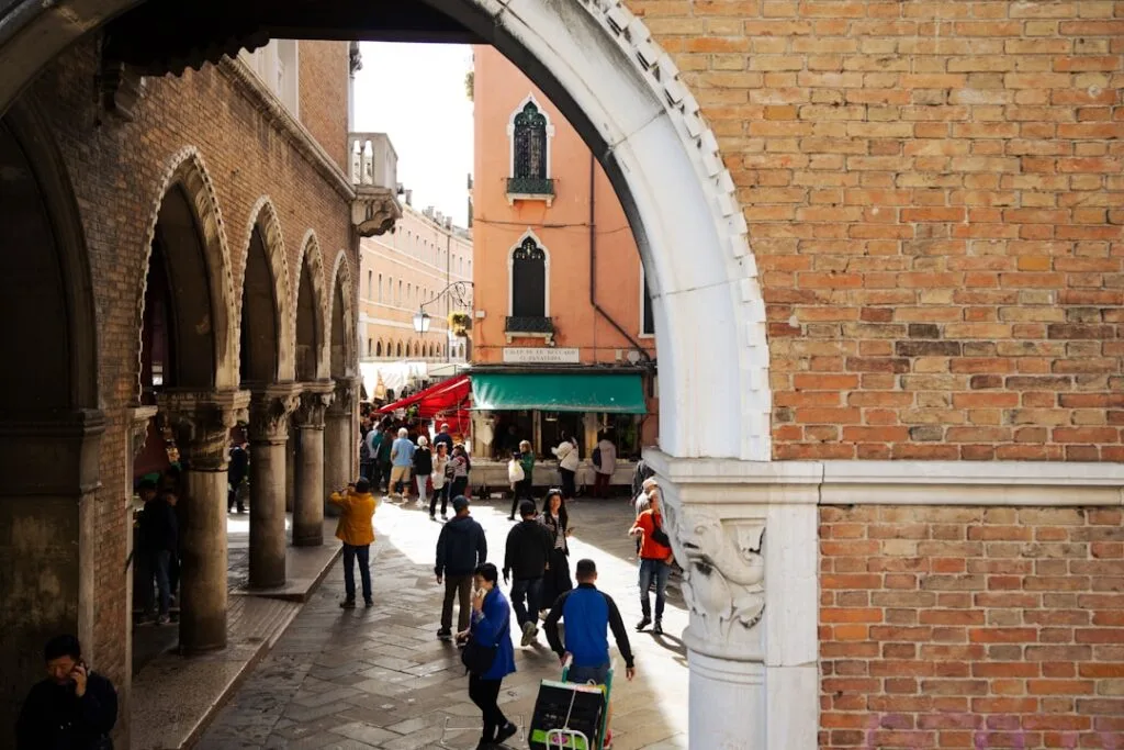 Arc en pierre ouvrant sur une ruelle animée près du marché à Venise