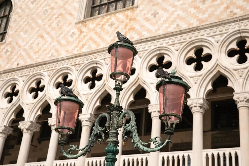 Lampadaire vénitien à verres roses avec pigeons devant le palais