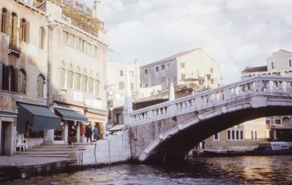 Petit pont en pierre à Venise bordé de boutiques et passants