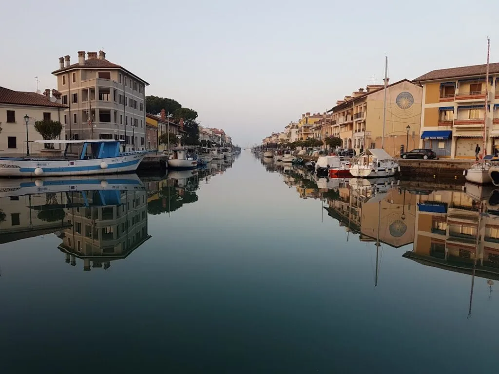 Canal calme bordé de maisons et de bateaux avec reflet symétrique