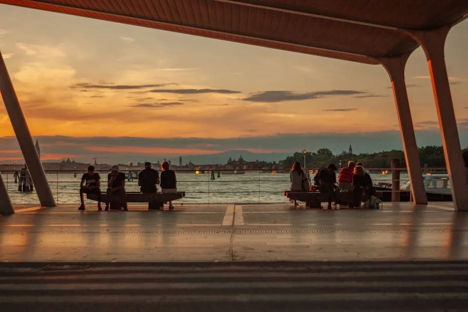 Abri de quai avec passagers regardant la lagune de Venise au coucher.