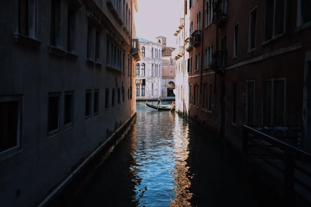 Gondolier naviguant dans un canal étroit entre bâtiments à Venise