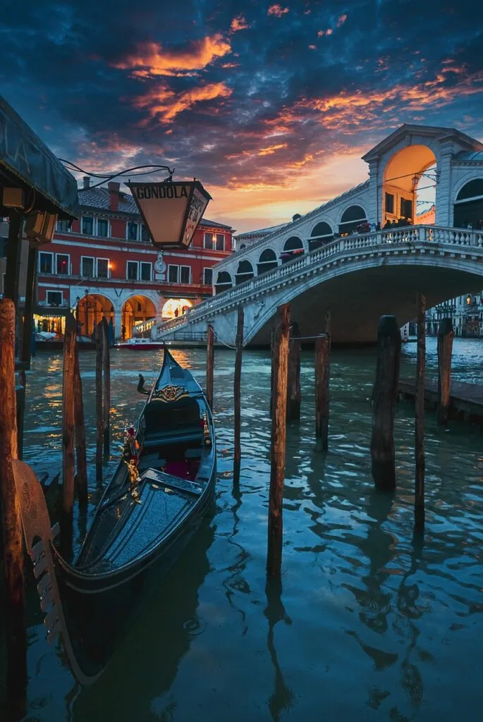 Gondole amarrée près du pont du Rialto sous un ciel enflammé