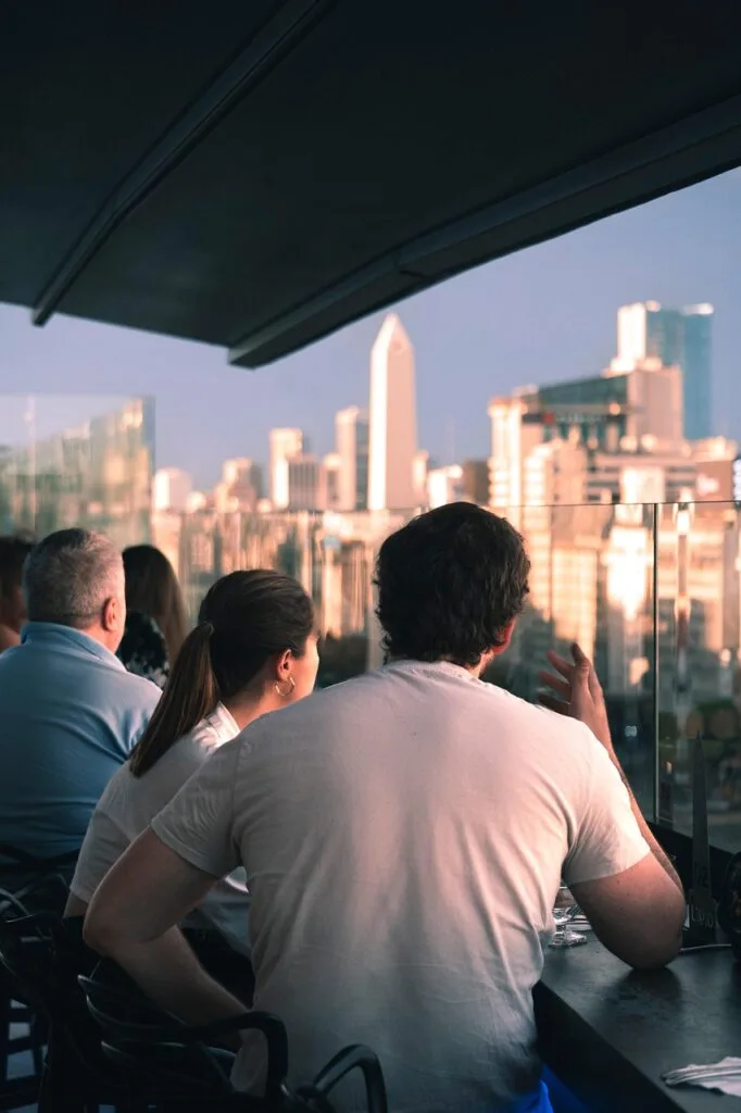 Personnes attablées sur la terrasse d'un hôtel, vue urbaine.