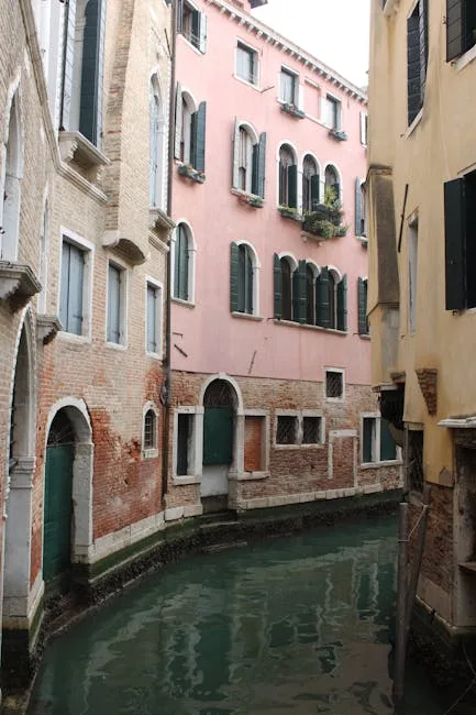 Canal étroit bordé d'immeubles roses aux volets verts à Venise