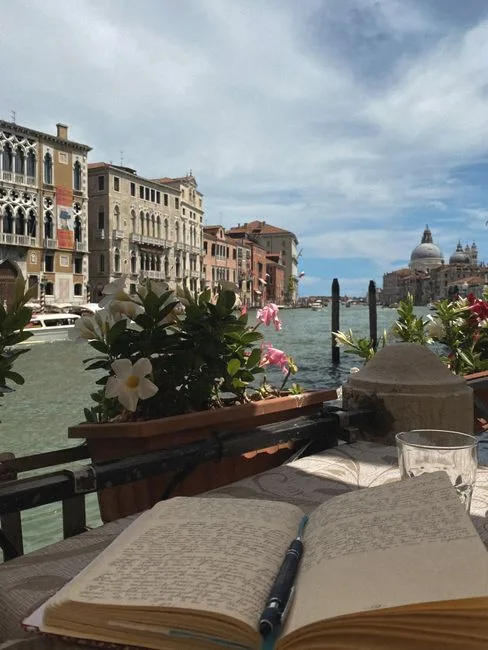 Carnet ouvert sur table au bord du Grand Canal à Venise, basilique Salute visible