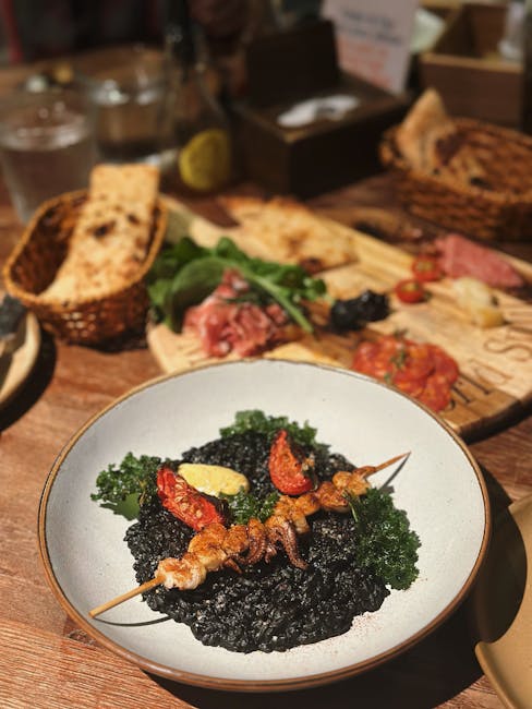 Zwarte inktvisrisotto met garnalenspies en broodplank op tafel in Split