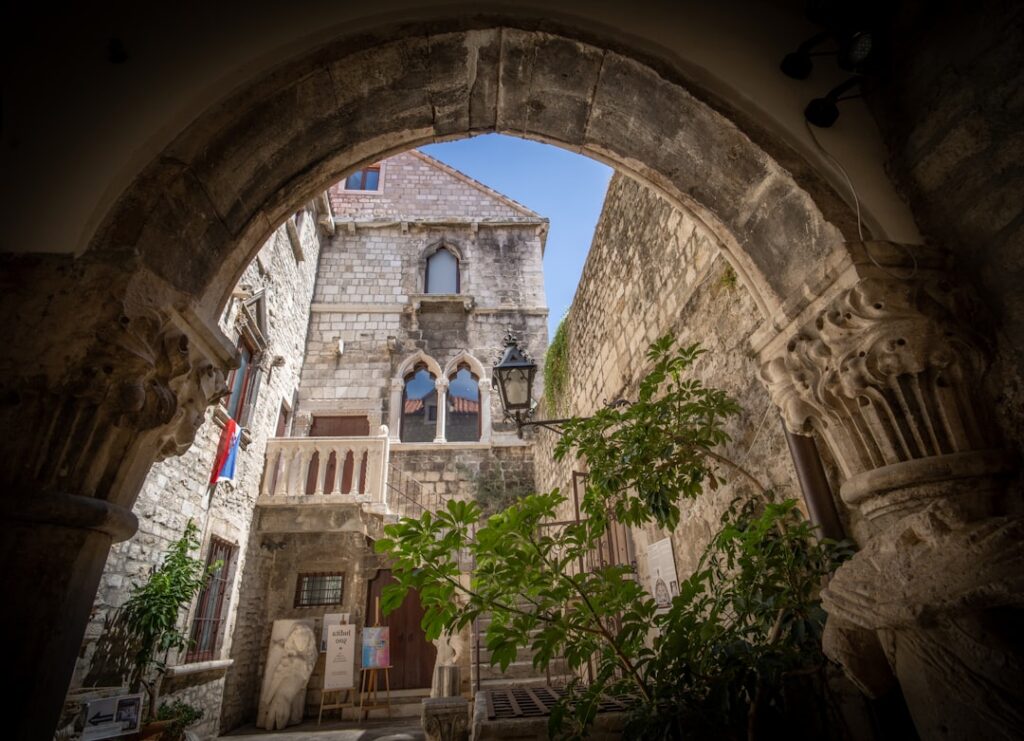 Gewölbter Steinbogen öffnet Blick auf historischen Innenhof in Split