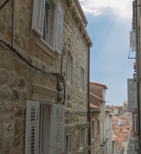Schmale Gasse mit steinernen Häusern und weißen Fensterläden in Split