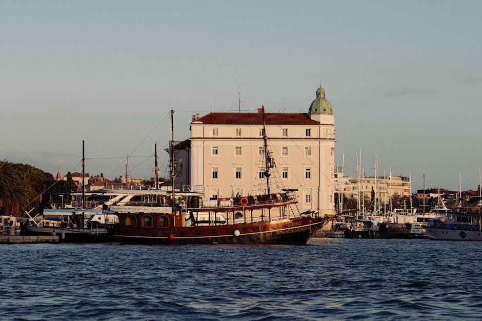 Historisch houten schip aangemeerd voor een groot gebouw in haven van Split
