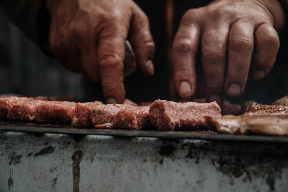 Mani che grigliano ćevapi su barbecue in strada a Spalato