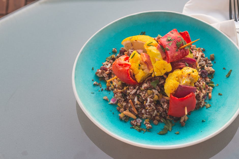 Colorful quinoa salad topped with cauliflower skewers on turquoise plate
