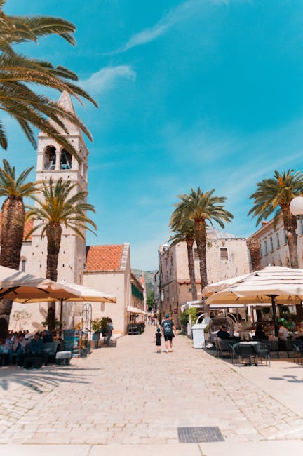 Open plein met palmbomen, terrassen en kerkklokkentoren in Split.