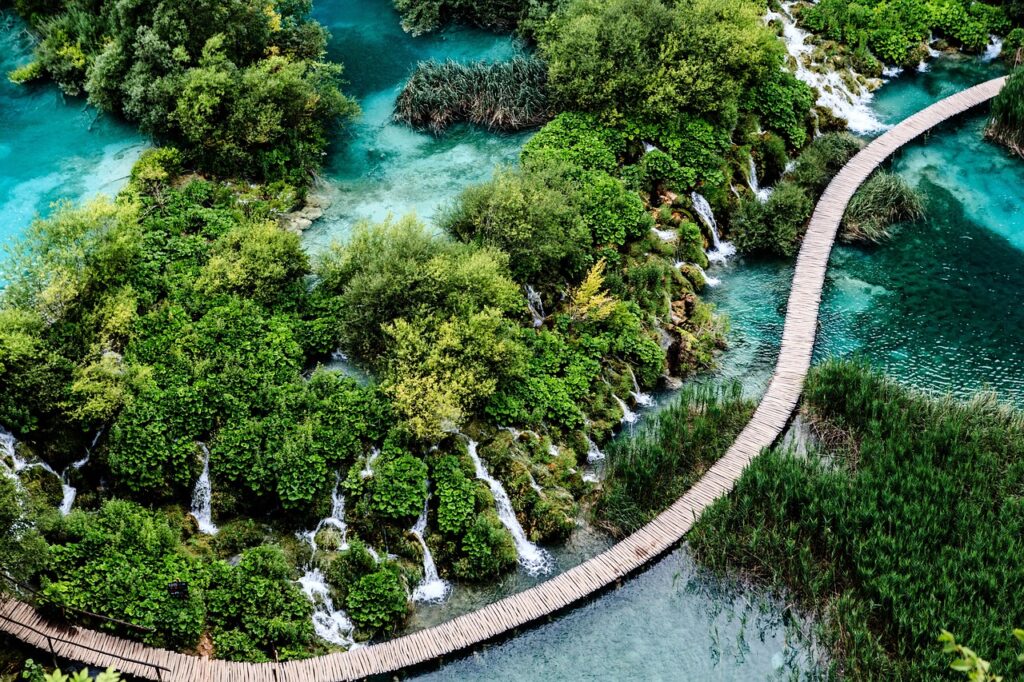 Close perspective of a wooden boardwalk through waterfalls and forest at Plitvice