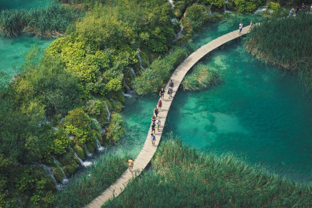 Tourists walking a wooden bridge over Plitvice lower lakes