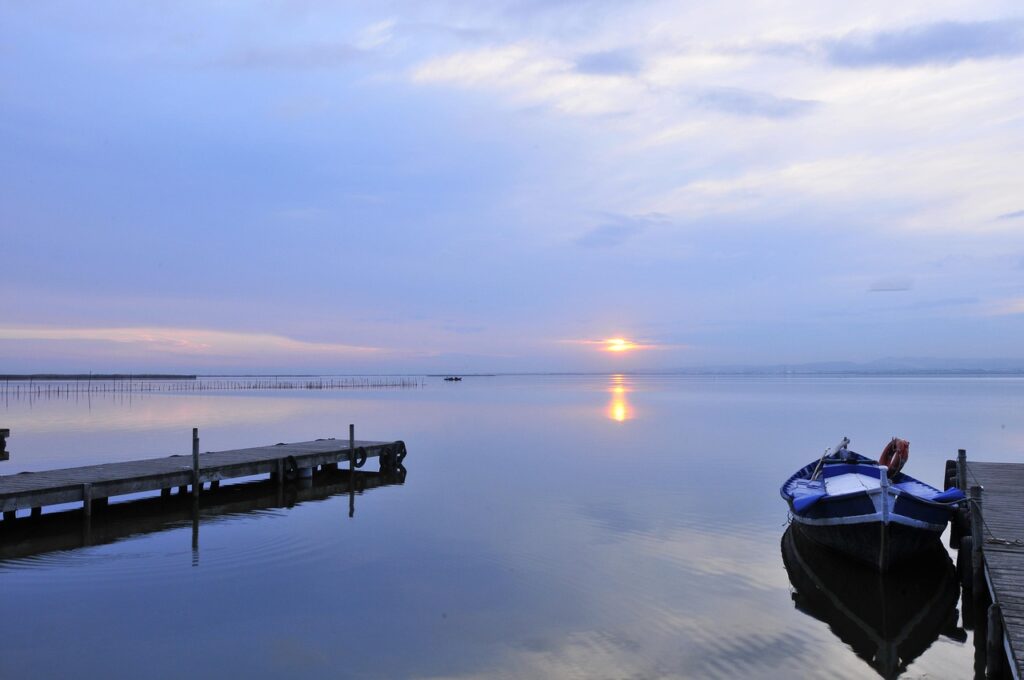 Barca al tramonto sull'Albufera con risaie sullo sfondo